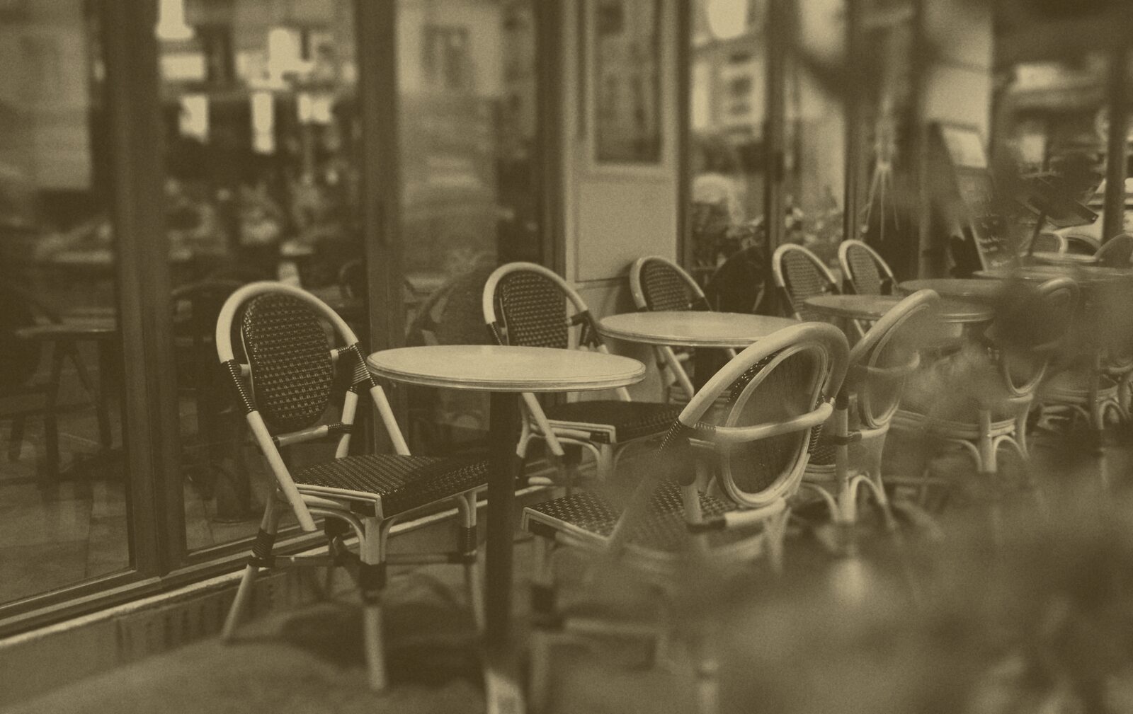 Empty rattan bistro chairs and round tables on a Paris café terrace