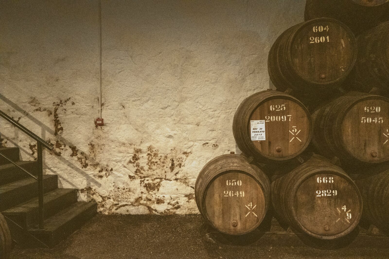 Numbered oak barrels stacked against a stone cellar wall