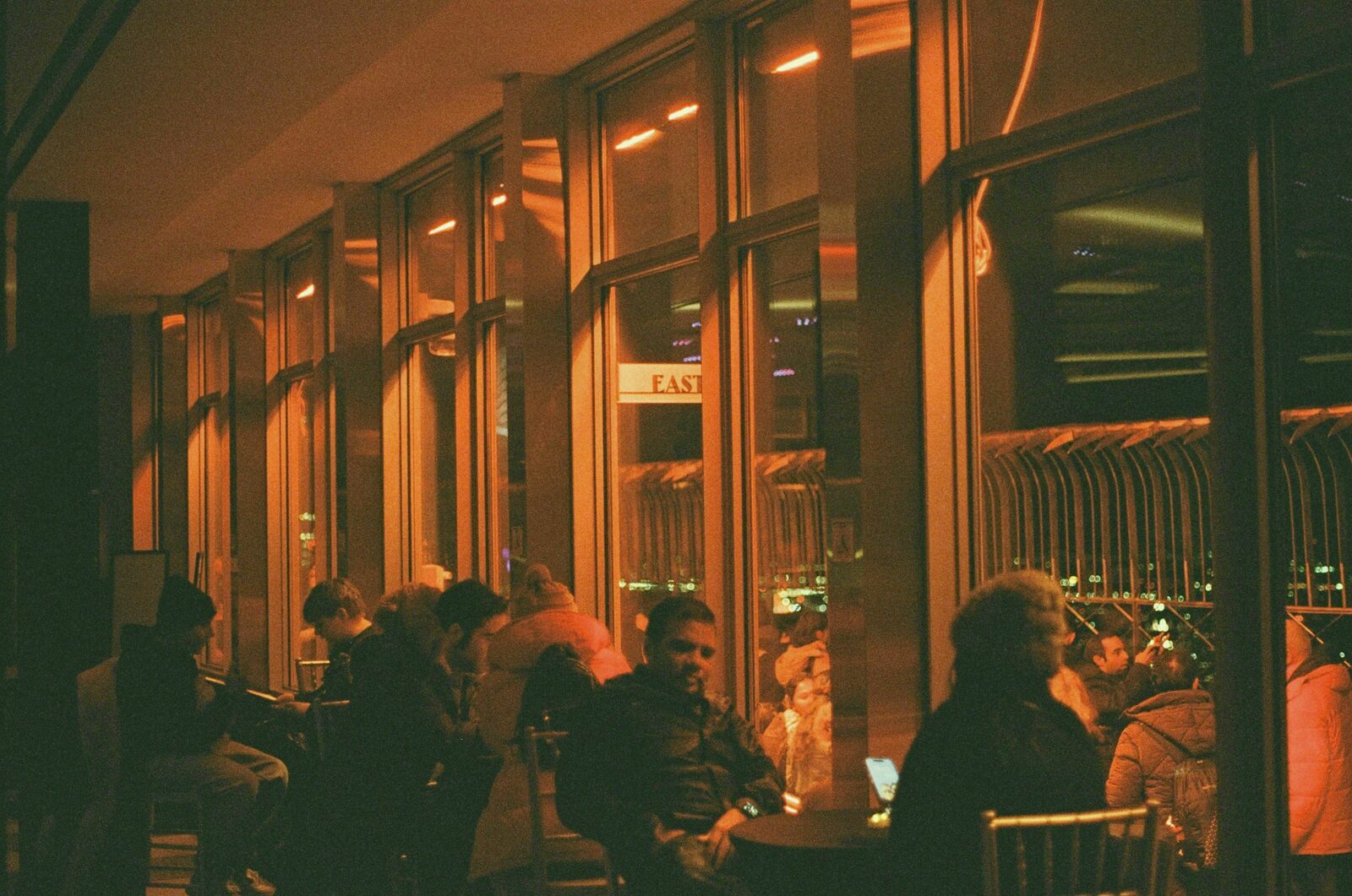 Guests seated on a covered rooftop terrace overlooking the city at night