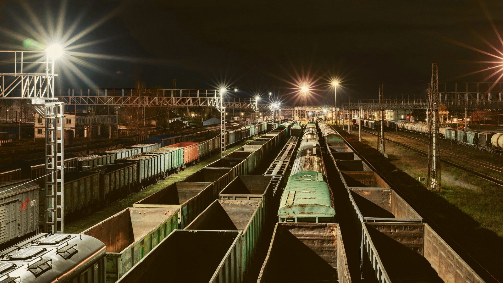 An elevated night view of a rail freight yard with rows of loaded cars.