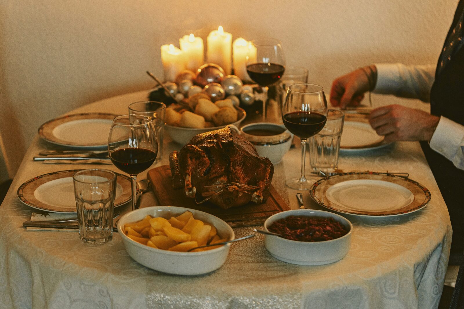A roast dinner spread on a table set with side dishes and stemmed glassware.