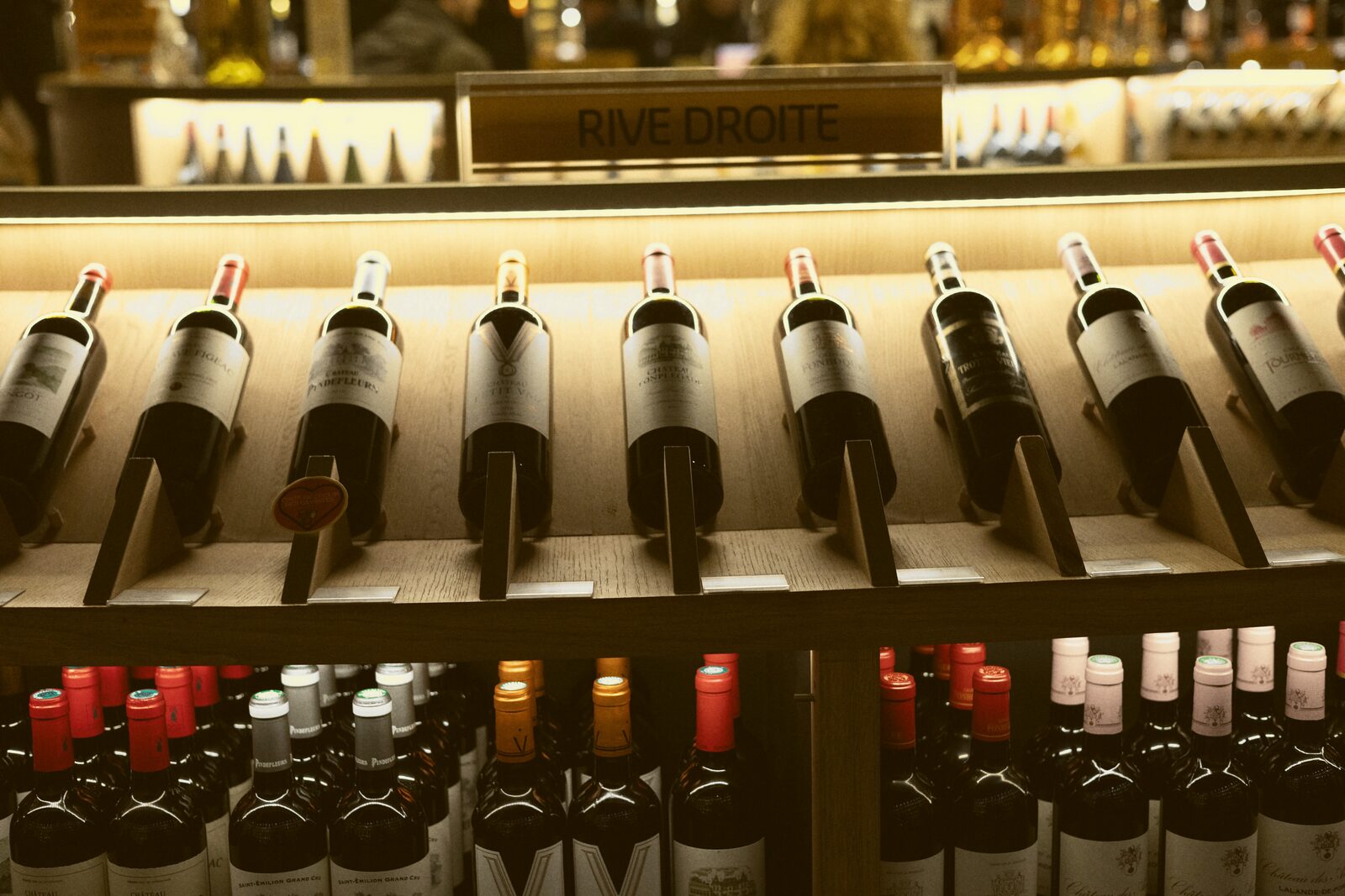 Wine bottles displayed on a lit shelf beneath a sign reading a wine region name.