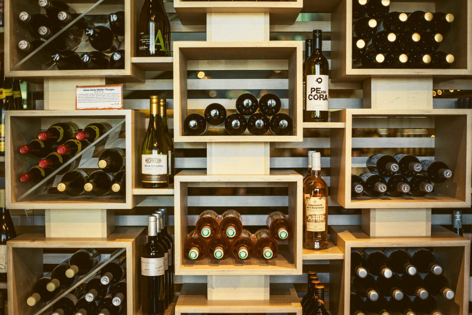 Wine bottles arranged on angled wooden retail shelving.