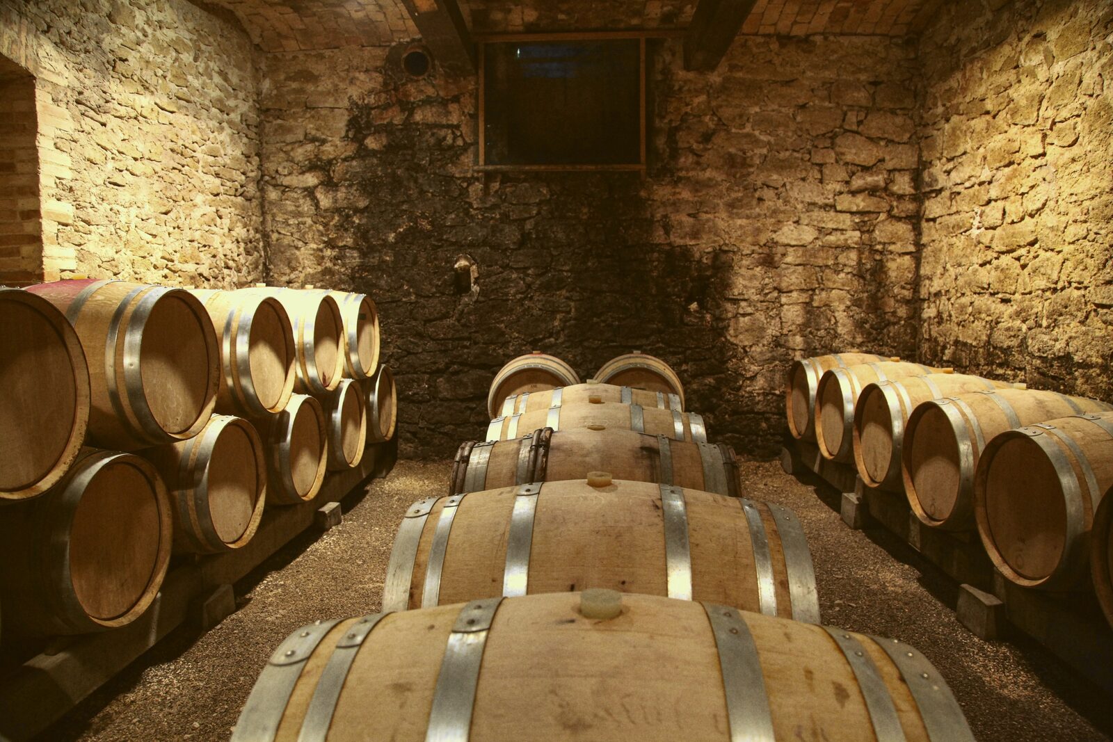 Oak barrels stacked along the stone walls of a small cellar room.